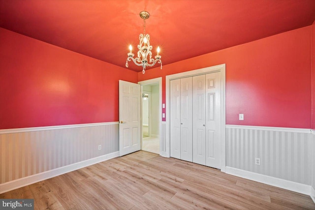 unfurnished bedroom with a chandelier, hardwood / wood-style flooring, and a closet