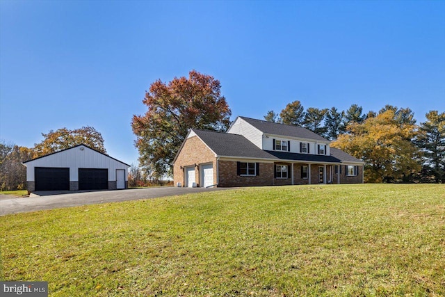 view of front of property with a garage, a front lawn, and an outbuilding