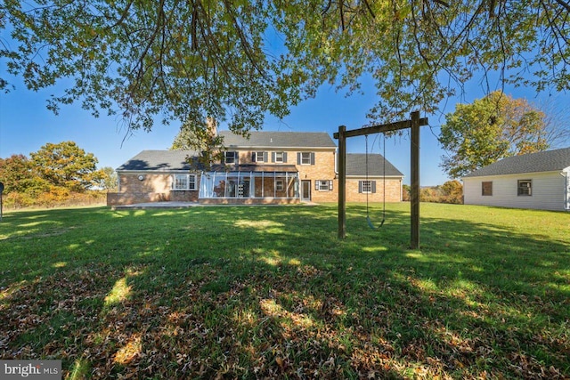 rear view of house featuring a yard and a sunroom