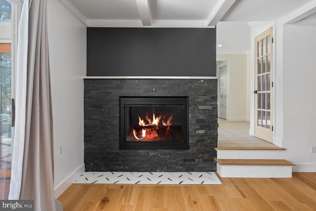 details featuring a stone fireplace, beamed ceiling, ornamental molding, and hardwood / wood-style floors