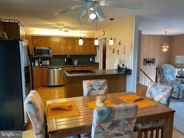 kitchen with kitchen peninsula, ceiling fan, appliances with stainless steel finishes, light hardwood / wood-style flooring, and decorative light fixtures