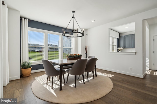 dining space with dark wood-type flooring, a healthy amount of sunlight, and an inviting chandelier