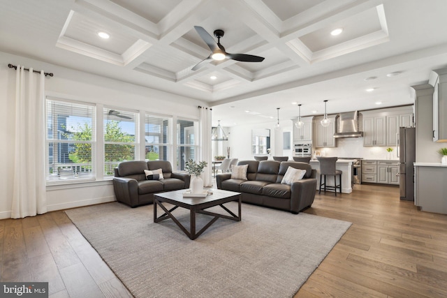 living room with light hardwood / wood-style floors, beamed ceiling, coffered ceiling, and ceiling fan