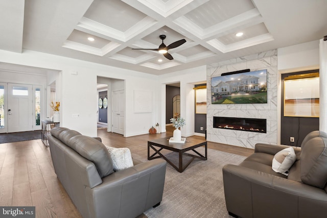 living room featuring a fireplace, ceiling fan, coffered ceiling, beam ceiling, and hardwood / wood-style flooring