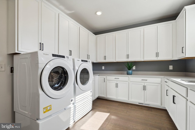 laundry room featuring cabinets, light hardwood / wood-style flooring, and washing machine and clothes dryer