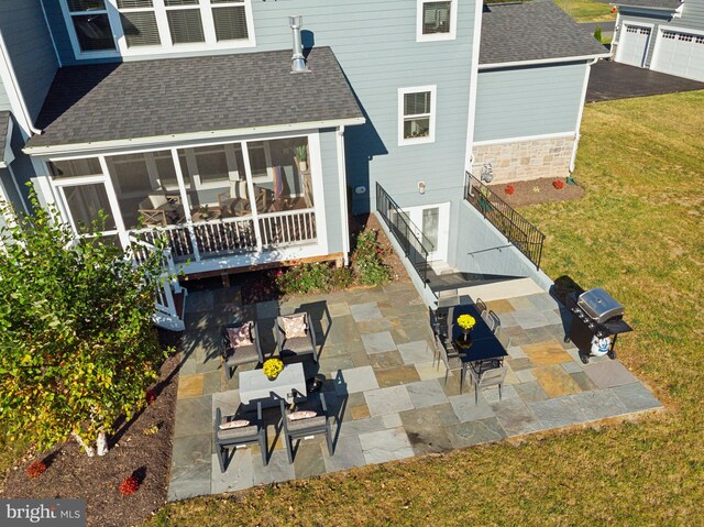 back of property with a yard, a patio, and a sunroom