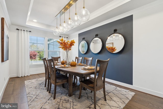 dining area featuring ornamental molding, hardwood / wood-style flooring, and a raised ceiling