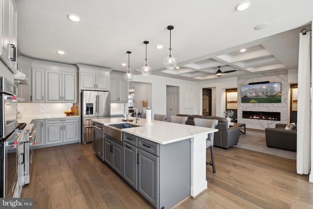 kitchen featuring a kitchen island with sink, sink, coffered ceiling, and hardwood / wood-style flooring