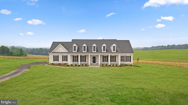 cape cod house with a rural view, a front yard, and covered porch