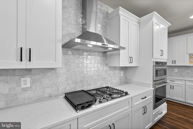 kitchen with wall chimney exhaust hood, white cabinets, backsplash, and gas stovetop