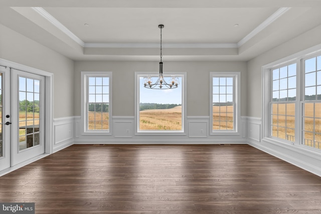 unfurnished dining area featuring dark wood-type flooring, a tray ceiling, and a healthy amount of sunlight