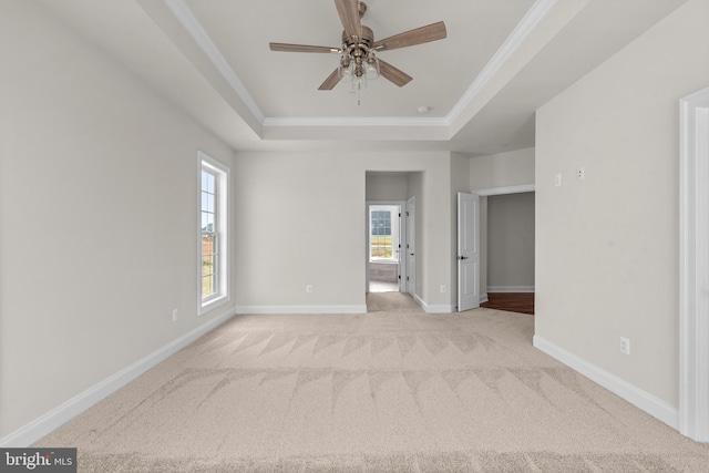 carpeted spare room with crown molding, ceiling fan, and a raised ceiling