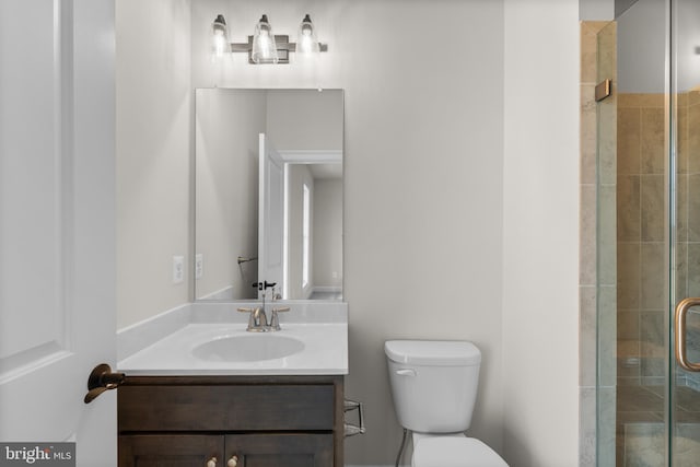 bathroom with vanity, toilet, and a shower with shower door