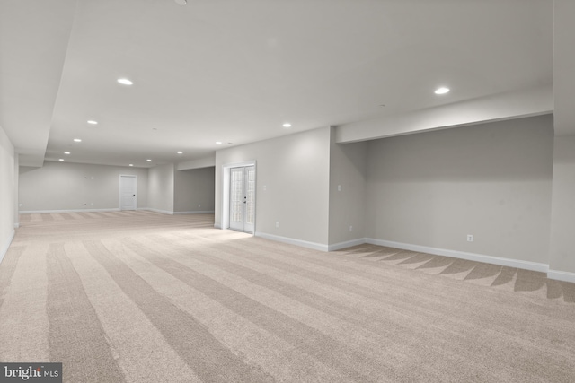 basement with french doors and light colored carpet