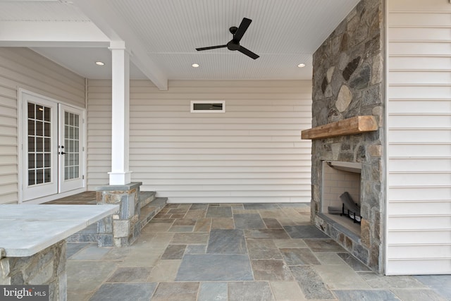 view of patio / terrace featuring french doors, ceiling fan, and an outdoor stone fireplace