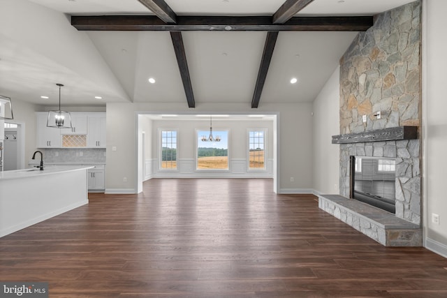 unfurnished living room featuring beamed ceiling, a notable chandelier, a fireplace, and dark hardwood / wood-style floors