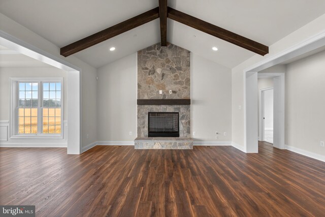 unfurnished living room featuring a stone fireplace, vaulted ceiling with beams, and dark wood-type flooring