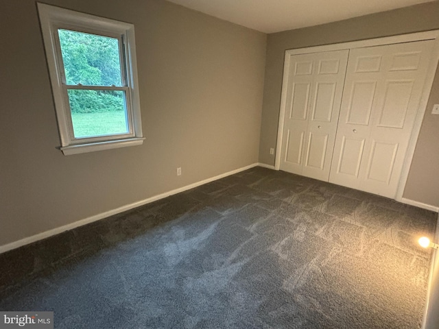 unfurnished bedroom with a closet and dark colored carpet