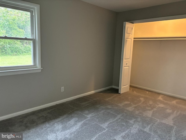 unfurnished bedroom featuring dark colored carpet and a closet