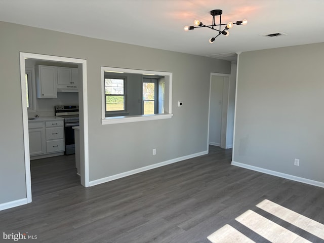 spare room with dark hardwood / wood-style flooring and a notable chandelier