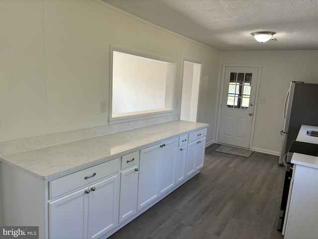 kitchen with light stone counters, stainless steel fridge, a textured ceiling, white cabinets, and range