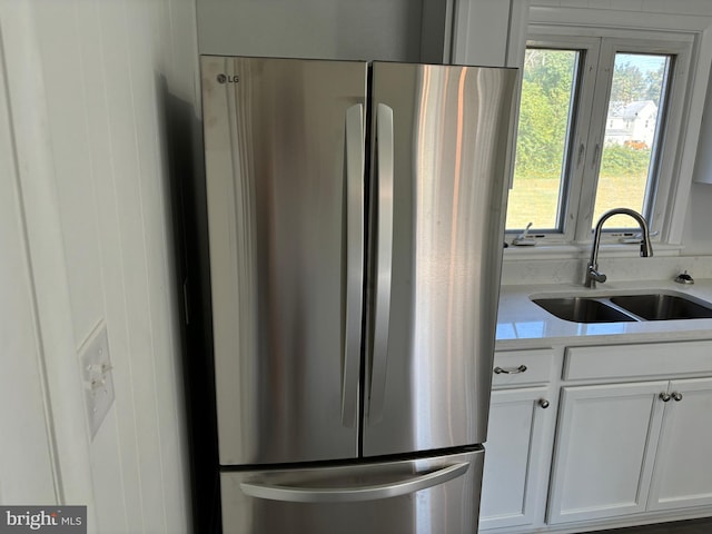 kitchen featuring white cabinets, stainless steel fridge, and sink