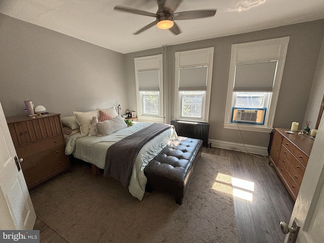 bedroom with ceiling fan, cooling unit, dark hardwood / wood-style flooring, and radiator