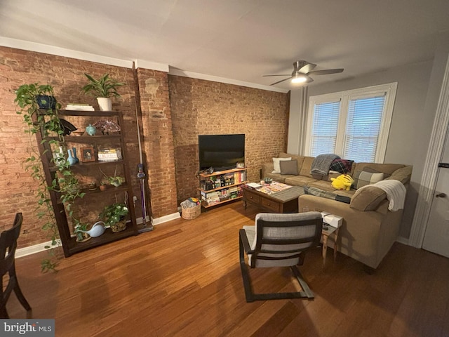 living room with ceiling fan, hardwood / wood-style floors, and brick wall