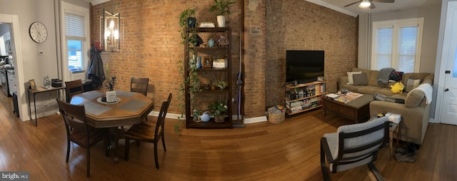 dining room with hardwood / wood-style flooring, ceiling fan, and brick wall