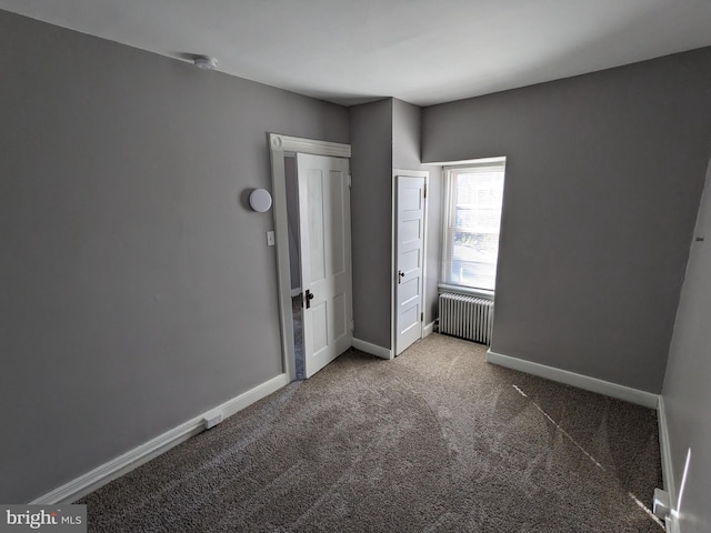 unfurnished bedroom with radiator and carpet floors