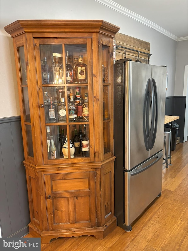 interior space featuring stainless steel fridge, crown molding, and light wood-type flooring