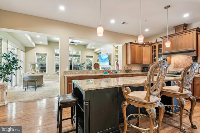 kitchen with light hardwood / wood-style floors, a breakfast bar area, pendant lighting, and backsplash