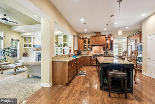 kitchen featuring tasteful backsplash, light stone countertops, appliances with stainless steel finishes, a breakfast bar, and dark hardwood / wood-style floors