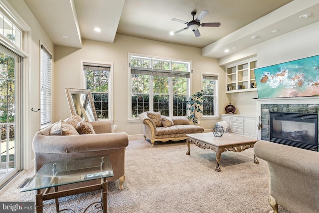 carpeted living room with ceiling fan, a wealth of natural light, and a fireplace