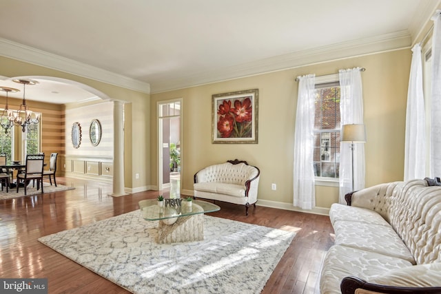 living room with ornate columns, crown molding, dark hardwood / wood-style flooring, and a chandelier