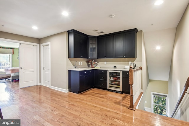 bar with light hardwood / wood-style flooring, sink, and beverage cooler