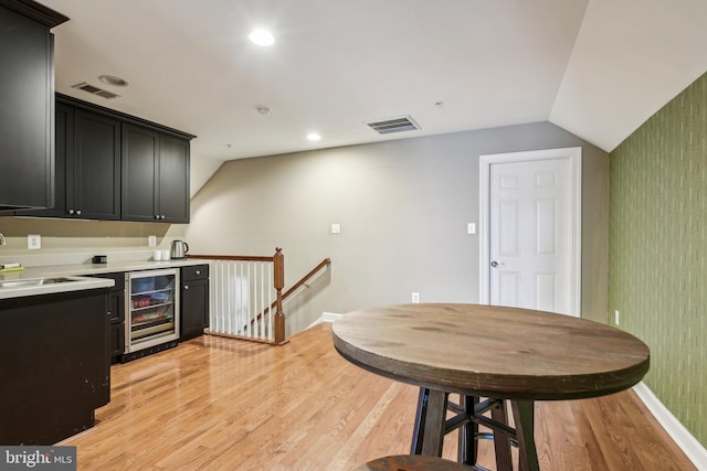 708 Church Rd S, Upper Marlboro, MD 20774 - kitchen featuring dark cabinets, visible vents, light wood-style floors, lofted ceiling, and wine cooler