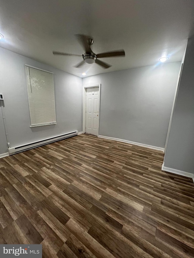 empty room with dark hardwood / wood-style floors, baseboard heating, and ceiling fan