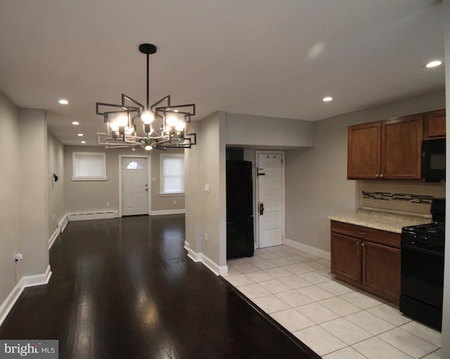 kitchen featuring black appliances, hanging light fixtures, baseboard heating, light tile patterned flooring, and a chandelier