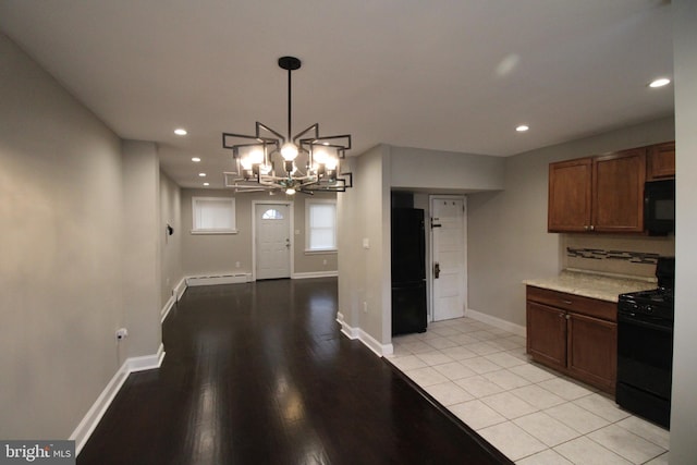 kitchen featuring black appliances, light tile patterned floors, decorative light fixtures, a baseboard radiator, and a notable chandelier