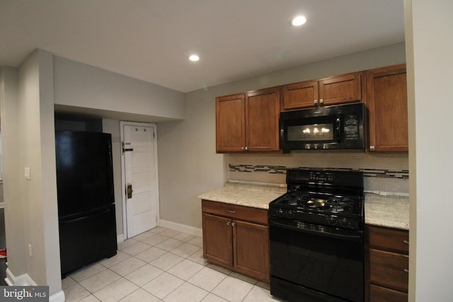 kitchen with black appliances, decorative backsplash, light tile patterned flooring, and light stone counters