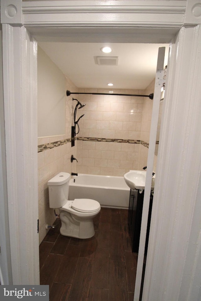 full bathroom with vanity, tile walls, hardwood / wood-style floors, toilet, and tiled shower / bath