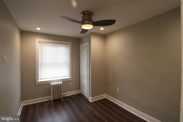 spare room with radiator heating unit, dark hardwood / wood-style flooring, and ceiling fan