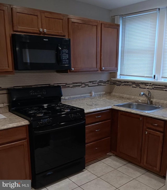 kitchen featuring backsplash, sink, light tile patterned floors, and black appliances