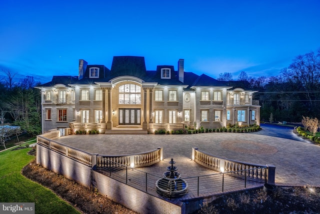 back house at dusk featuring french doors and a balcony