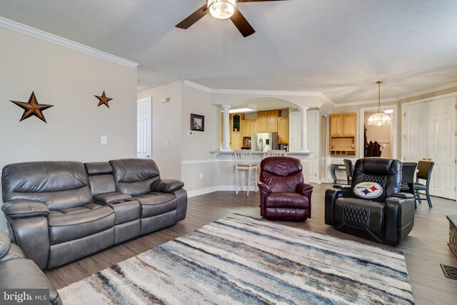 living room featuring decorative columns, dark wood-type flooring, and ornamental molding