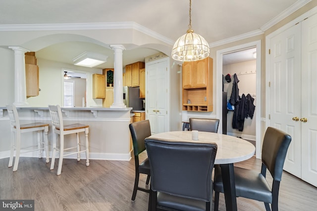 dining area featuring ceiling fan with notable chandelier, light hardwood / wood-style floors, ornate columns, and ornamental molding