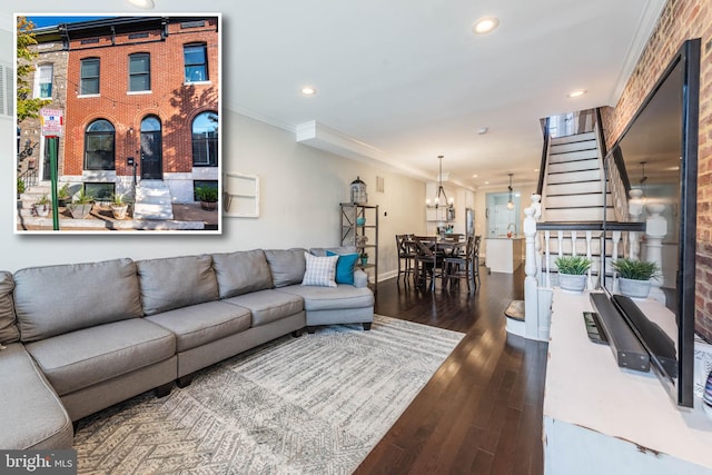 living room with wood-type flooring, ornamental molding, and an inviting chandelier