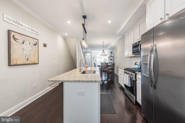 kitchen featuring appliances with stainless steel finishes, white cabinetry, hanging light fixtures, and an island with sink