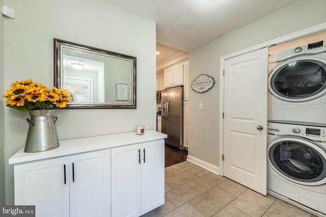 washroom featuring stacked washer and dryer and light tile patterned floors